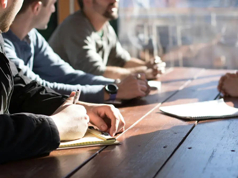 Reunión de trabajo alrededor de una mesa con cuadernos y bolígrafos